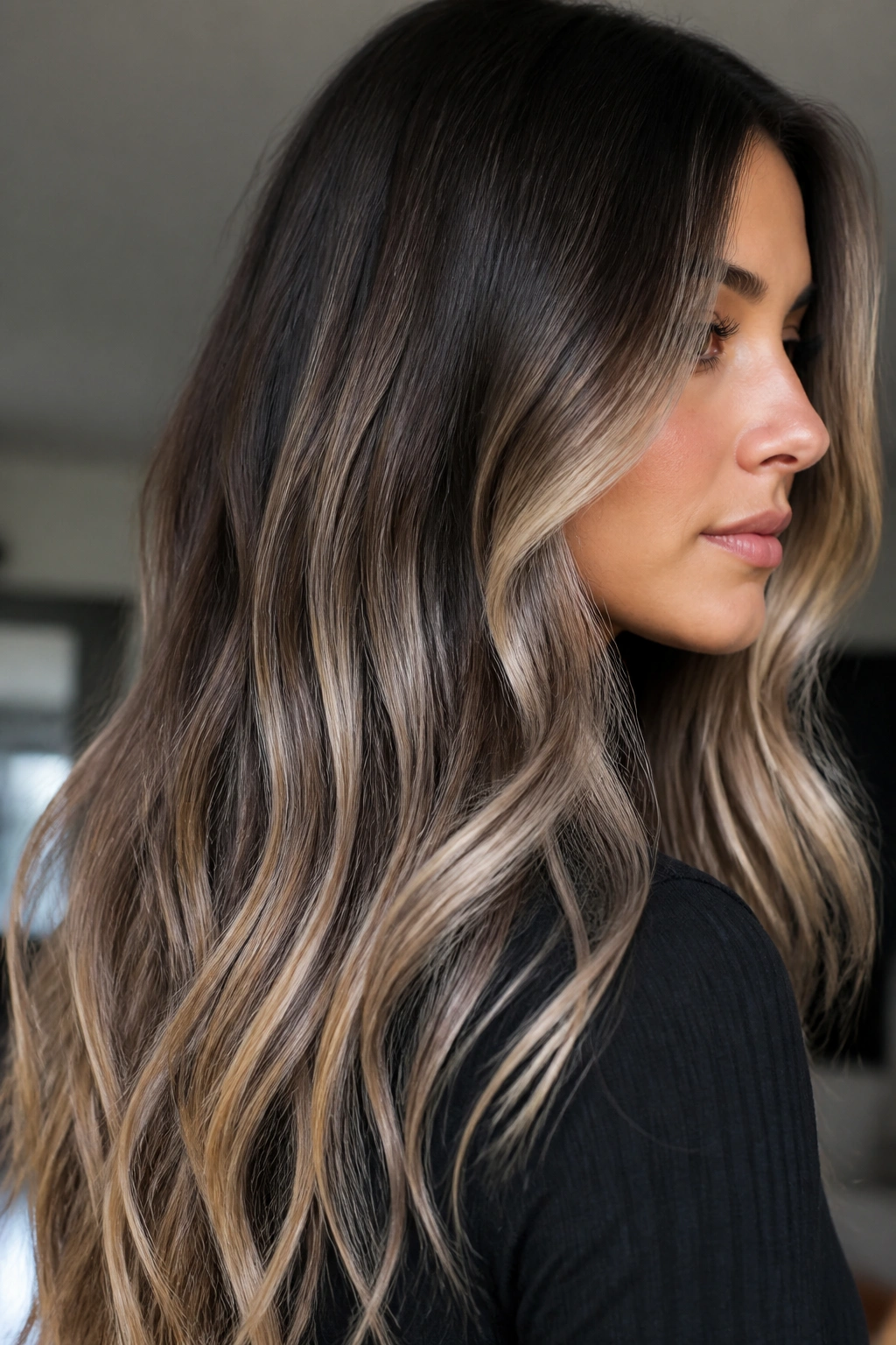 Side-profile of a real woman with ash beige balayage on long brunette hair