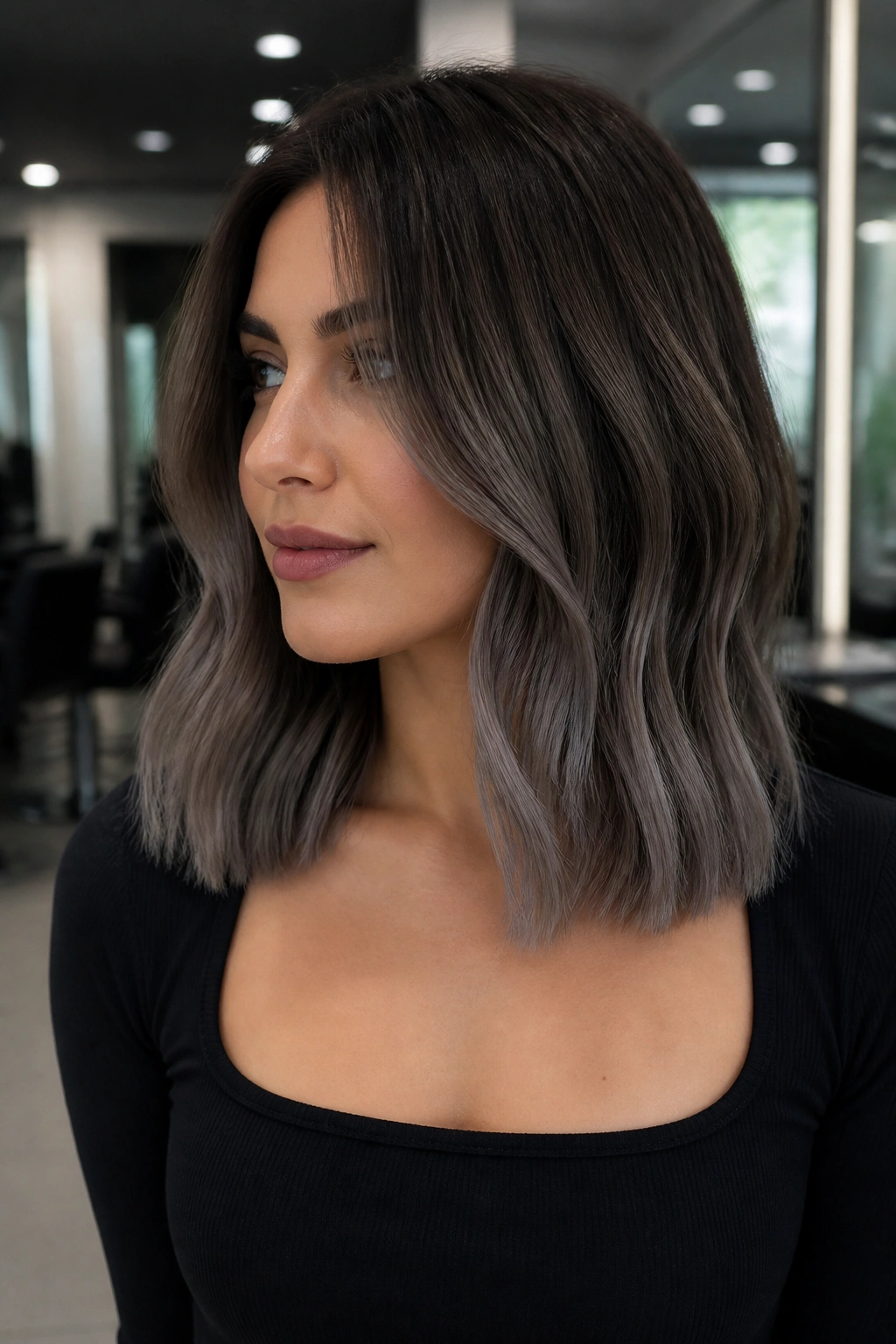 Close-up portrait of a woman with ash brown balayage and cool smoked-out ends.