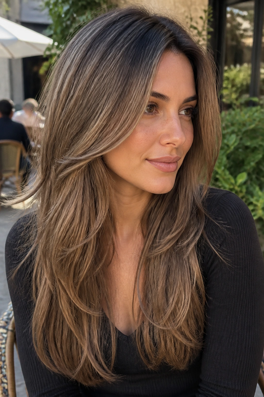 Close-up of a real woman with an ash brown shadow root and long layered hair.