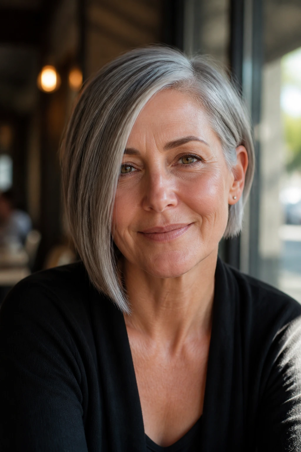 Close-up of a real woman with an asymmetrical gray bob in a sunlit cafe