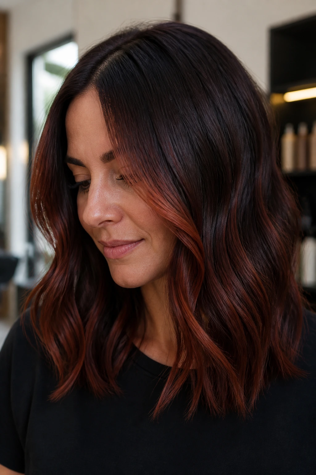 Close-up of a real woman with deep auburn balayage highlighting around the face.