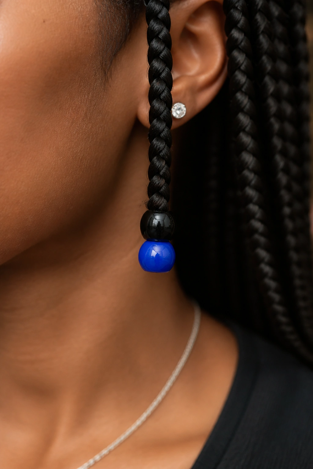 Close-up of a braid with a black bead and a single cobalt accent bead at the tip