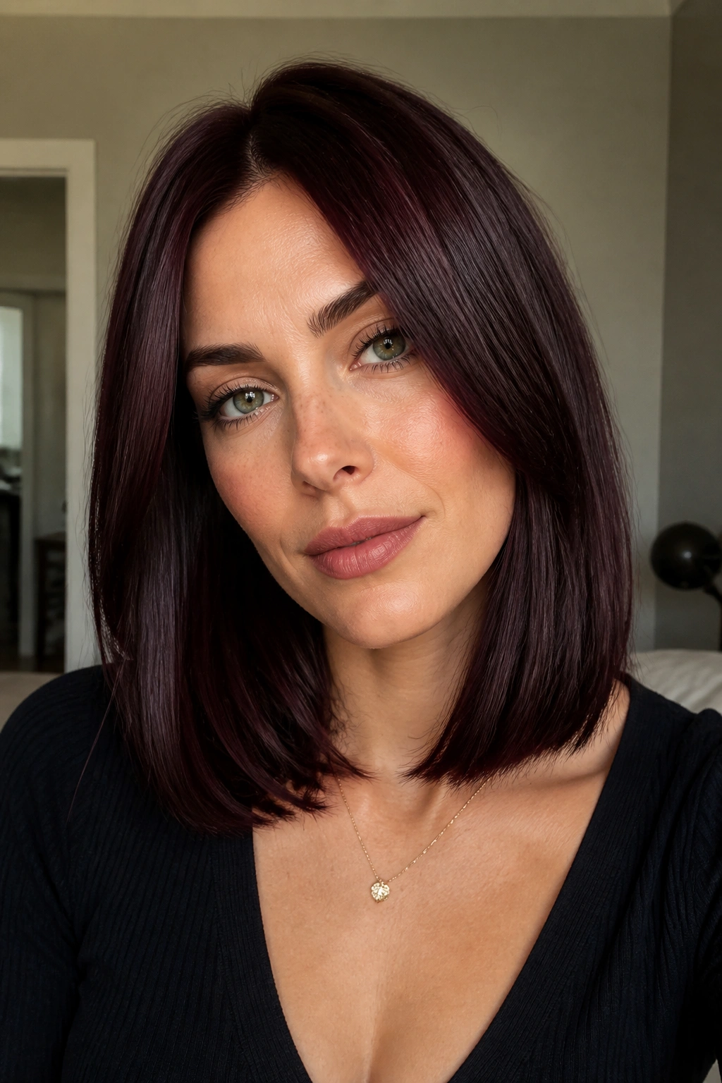 Real woman with a blunt black cherry lob under soft indoor lighting
