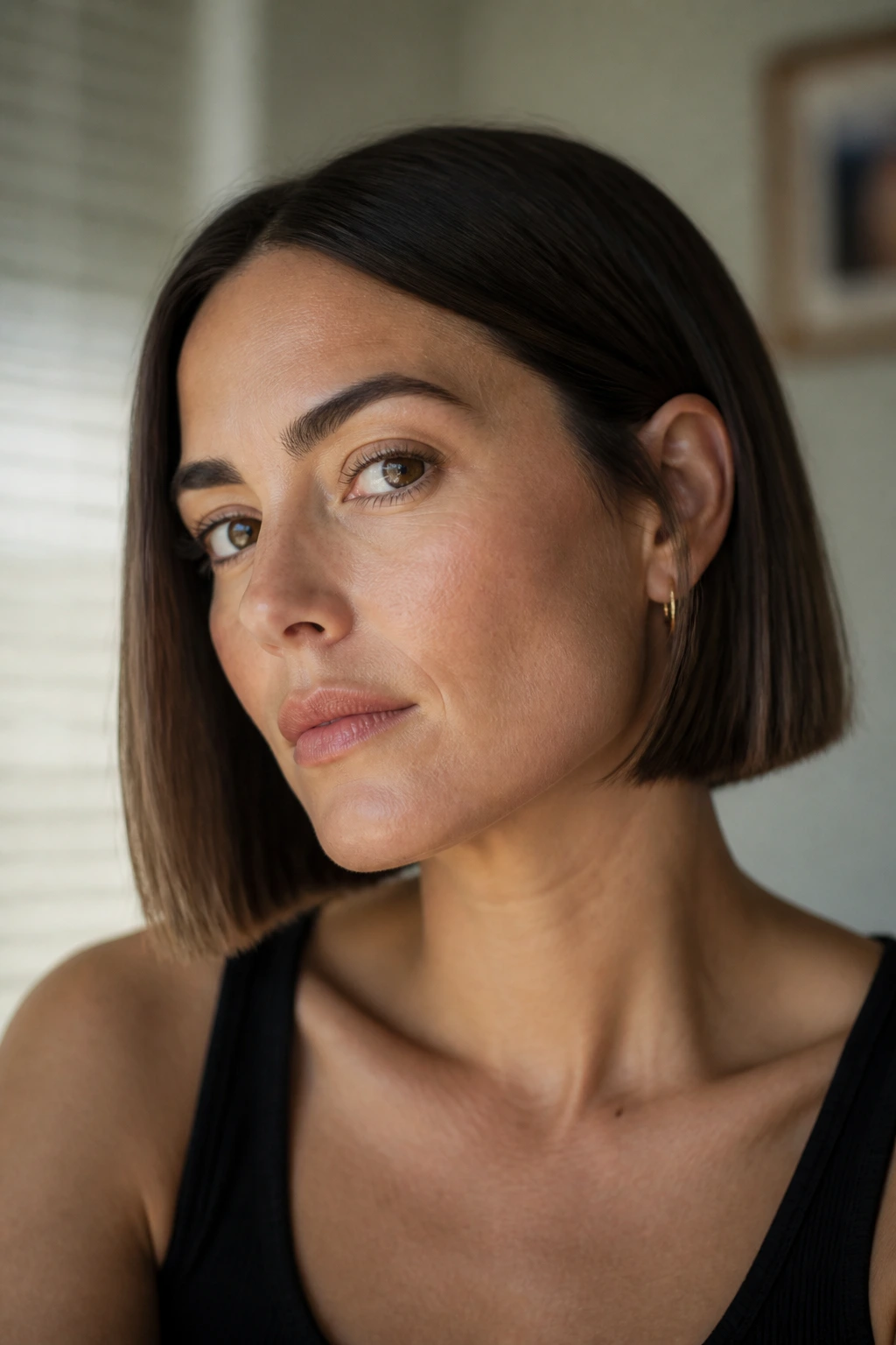 Close-up portrait of a real woman with a blunt earlobe-length bob in soft window light