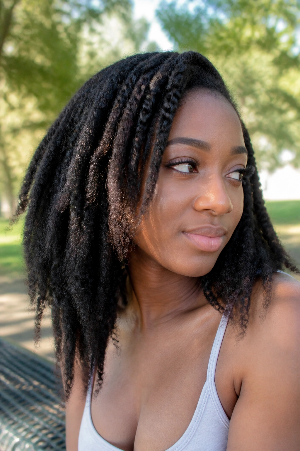 Close-up portrait of a real woman with a braid-out and stretched ends in natural sunlight