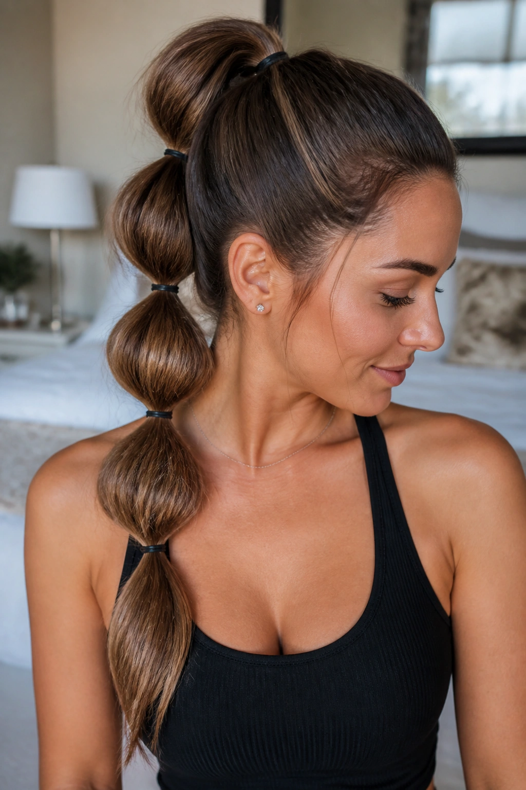 Close-up of real woman with bubble ponytail showing segmented bubbles along long hair in warm window light