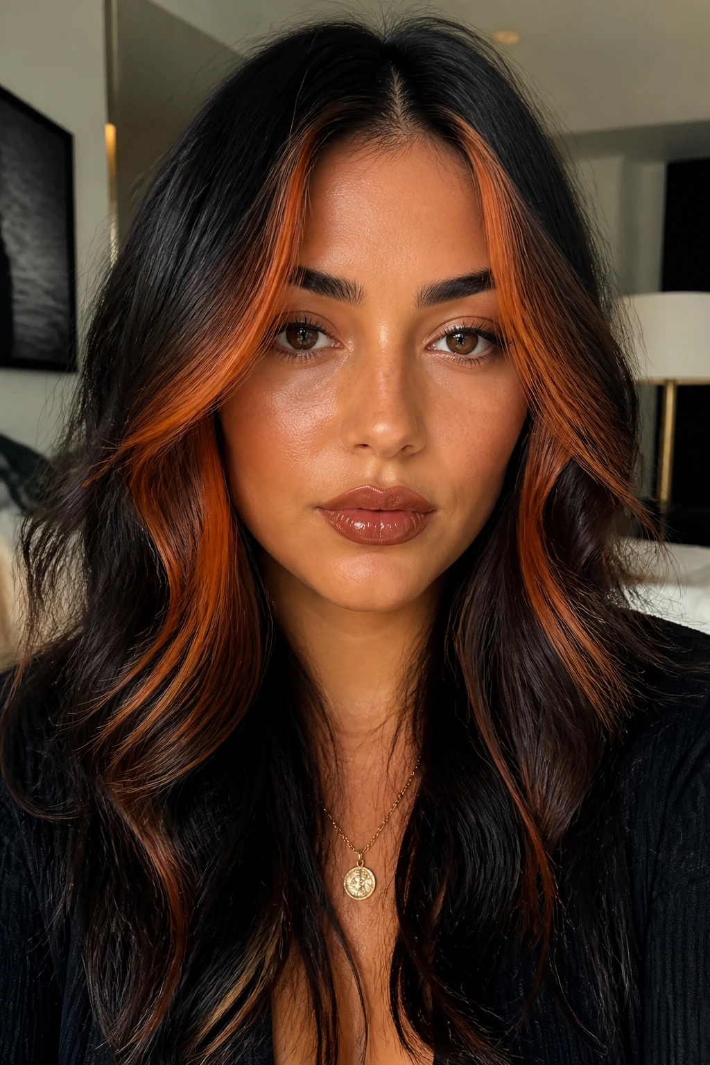 Close-up of burnt orange face-framing strands against dark hair.