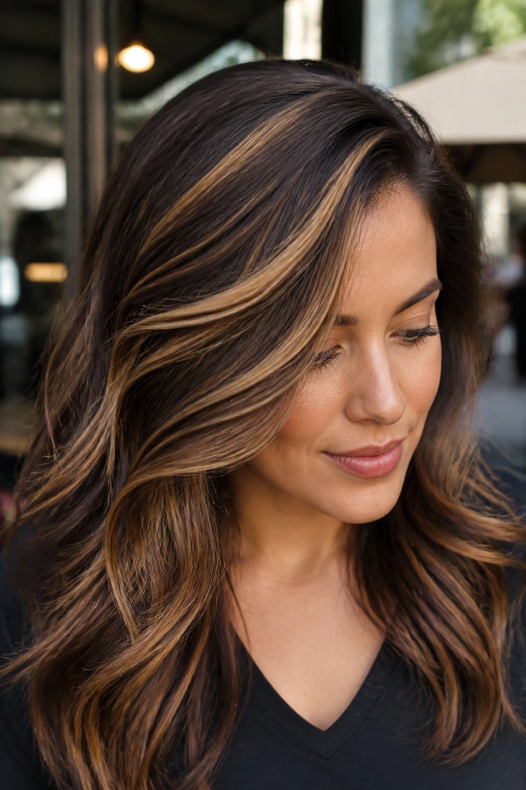 Portrait of a real woman with side-swept caramel ribbon highlights following the part diagonal.