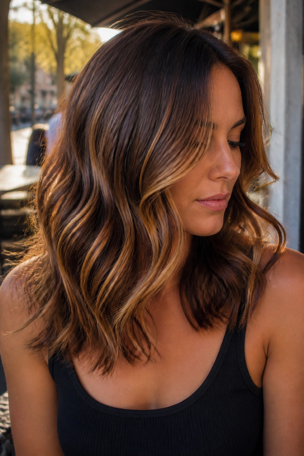 Medium close-up of a real woman with caramel swirl brown hair in warm outdoor light