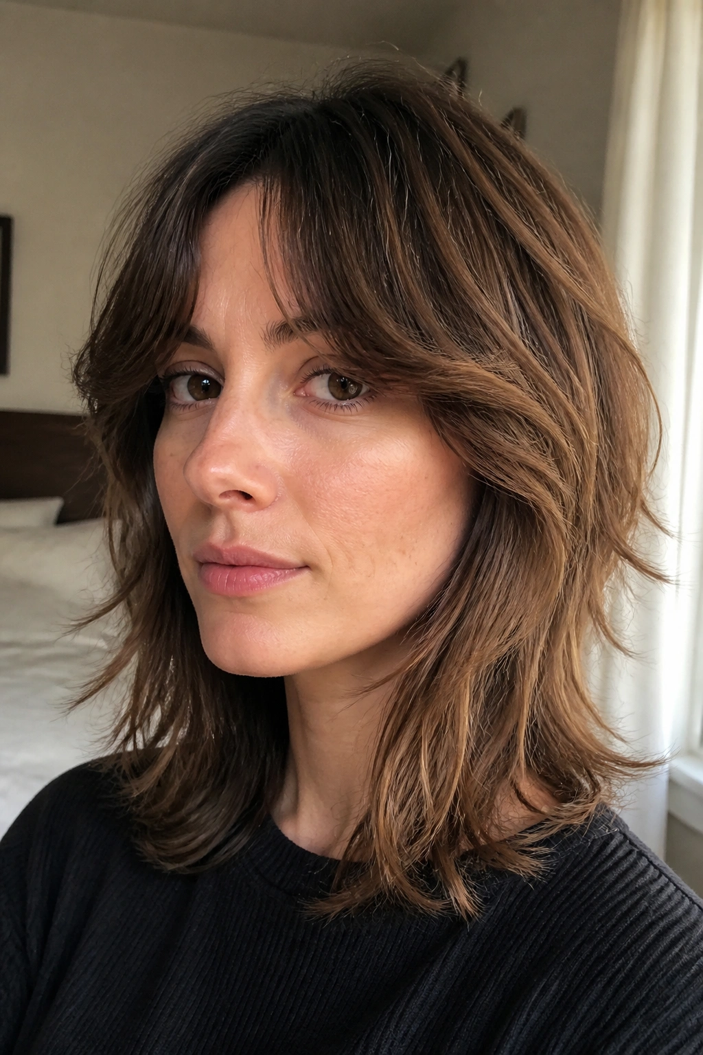 Close-up portrait of a real person with classic shag and curtain bangs in warm window light