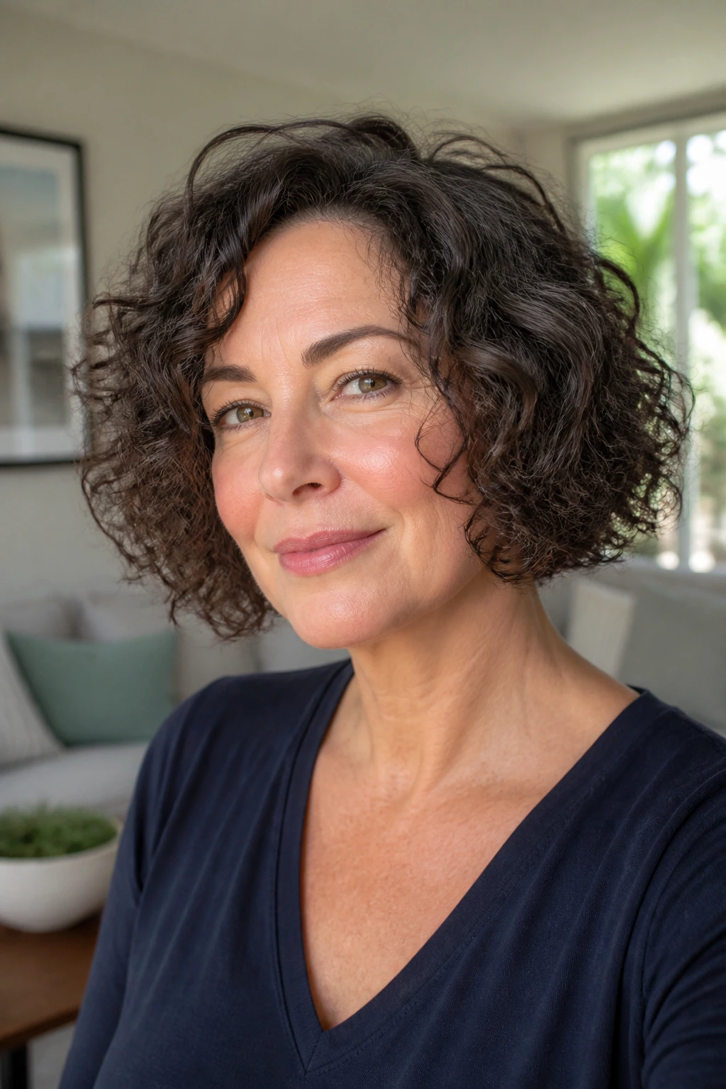 Close-up portrait of a real woman with a curly chin-length bob in bright indoor light