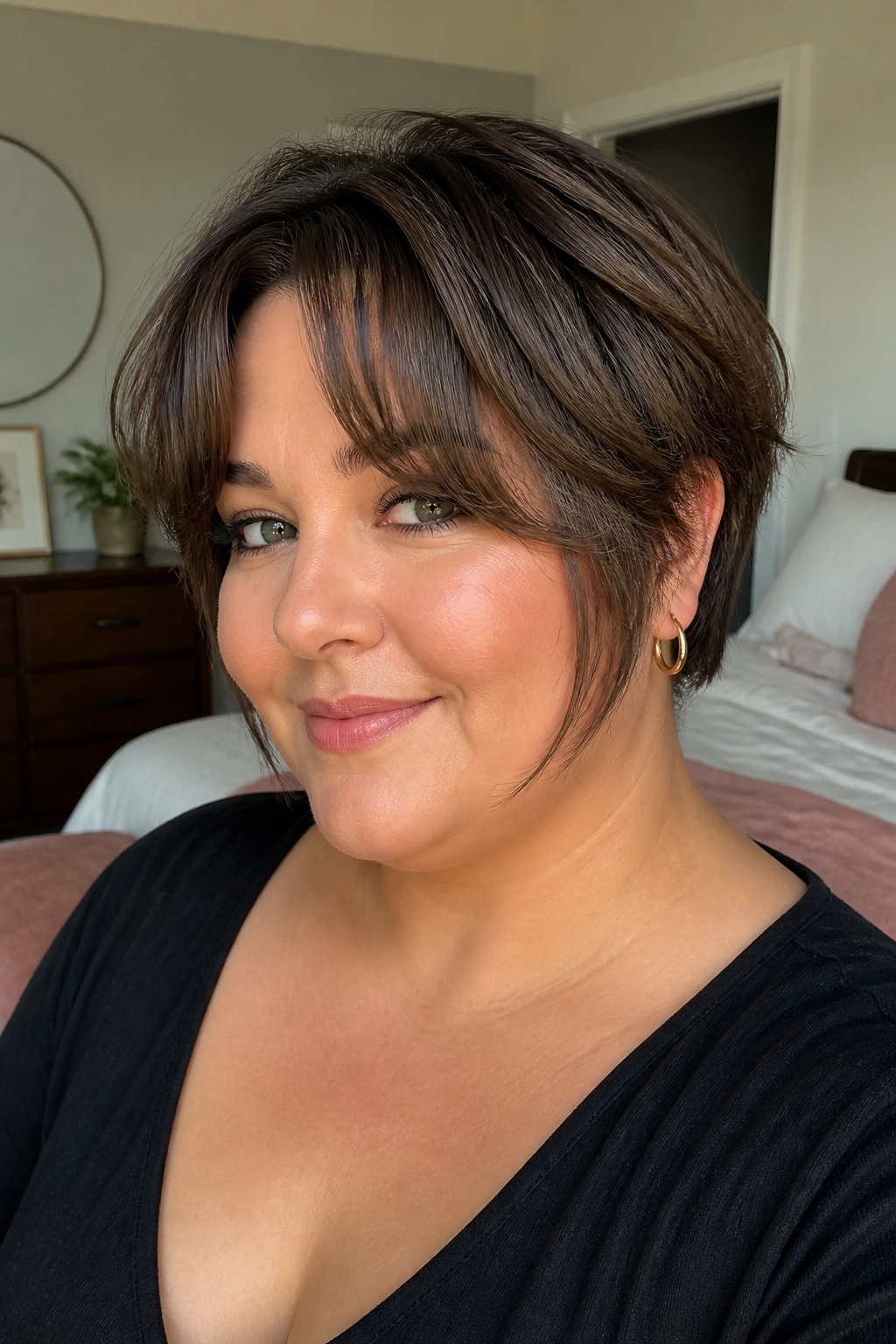 Woman with curtain bangs and face-framing pieces in a cozy bedroom.