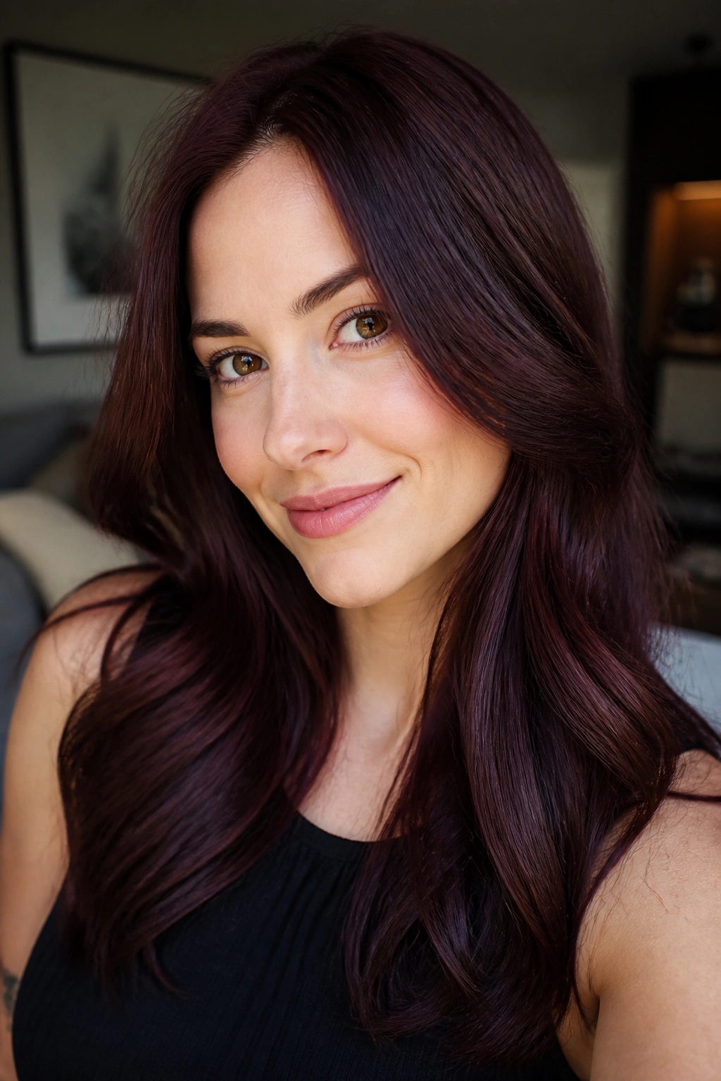 Close-up portrait of a real woman with dark cherry brown hair in warm window light