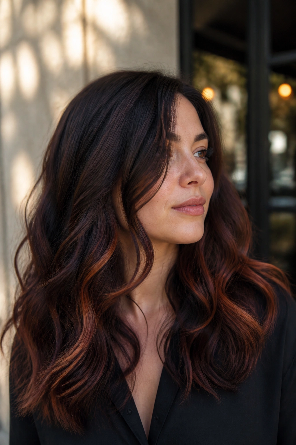 Real woman showing copper peekaboo beneath dark roast brunette in wavy hair
