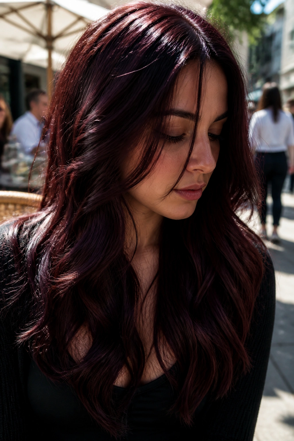 Close-up of a real person with deep burgundy cherry-cola hair in sunlight.