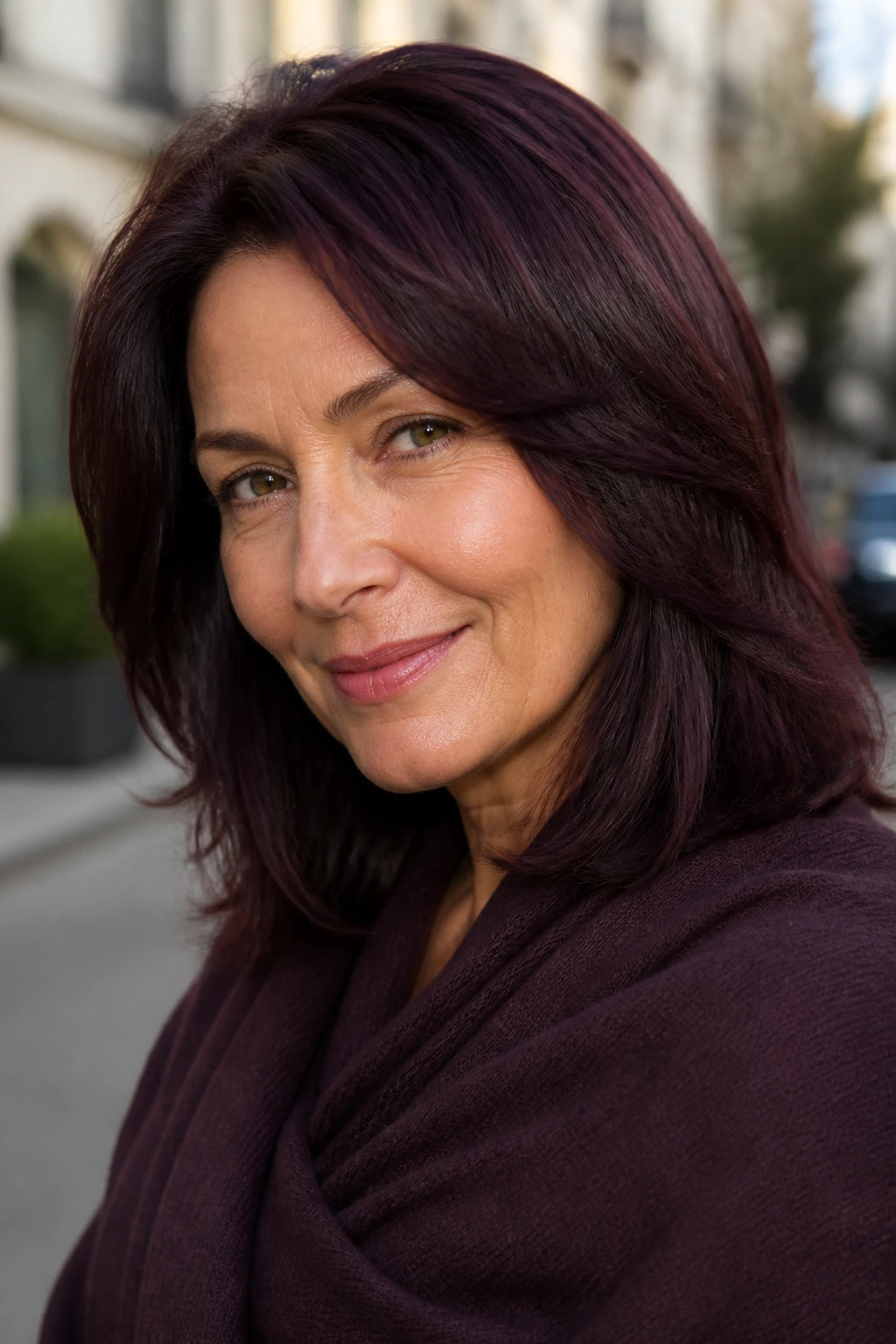 Close-up portrait of a real woman with Deep Plum-Brown hair with cooler edge in morning light.