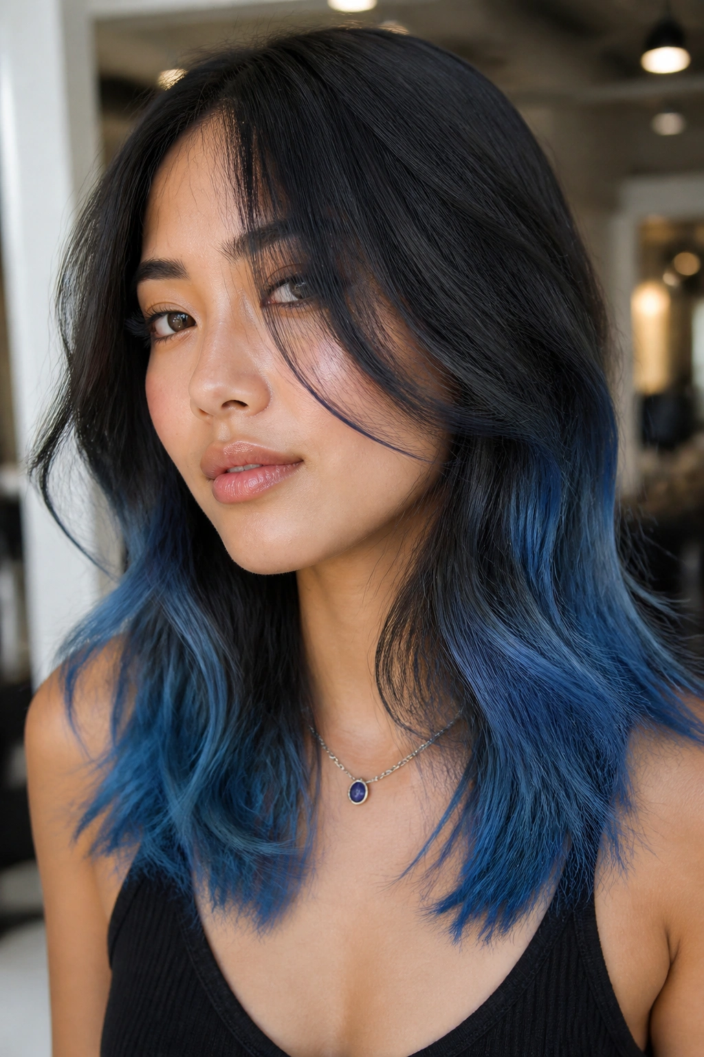 Close-up of a real person with denim blue hair ends on a layered cut in a salon