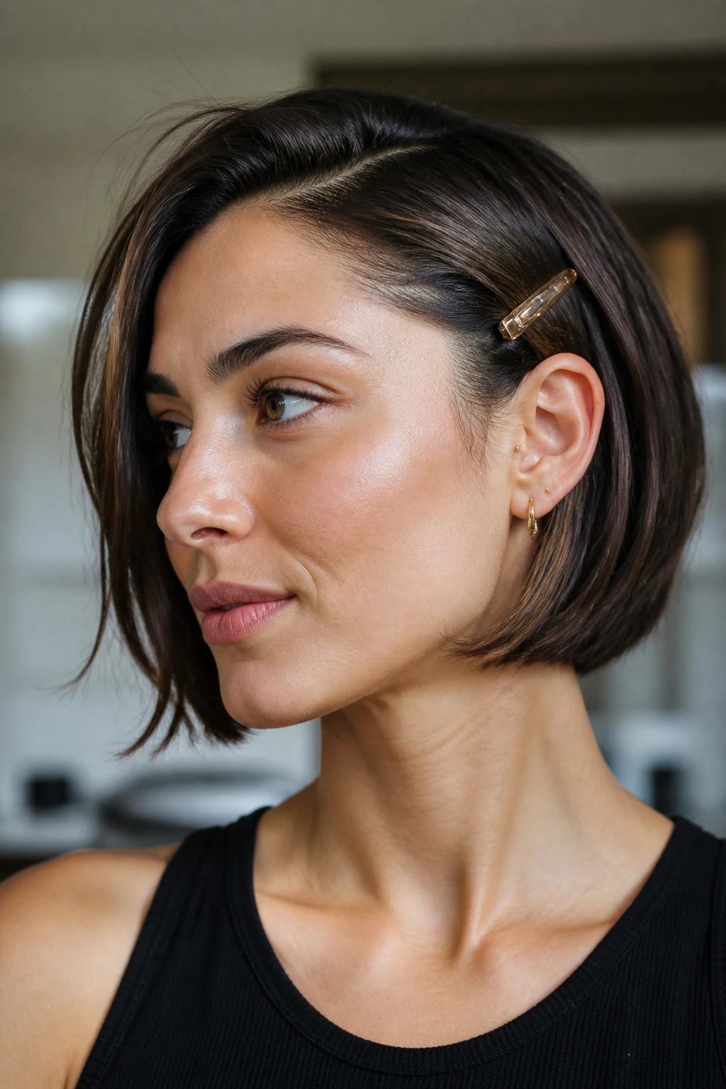 Portrait of a woman with ear-tucked bob and visible hair clip.