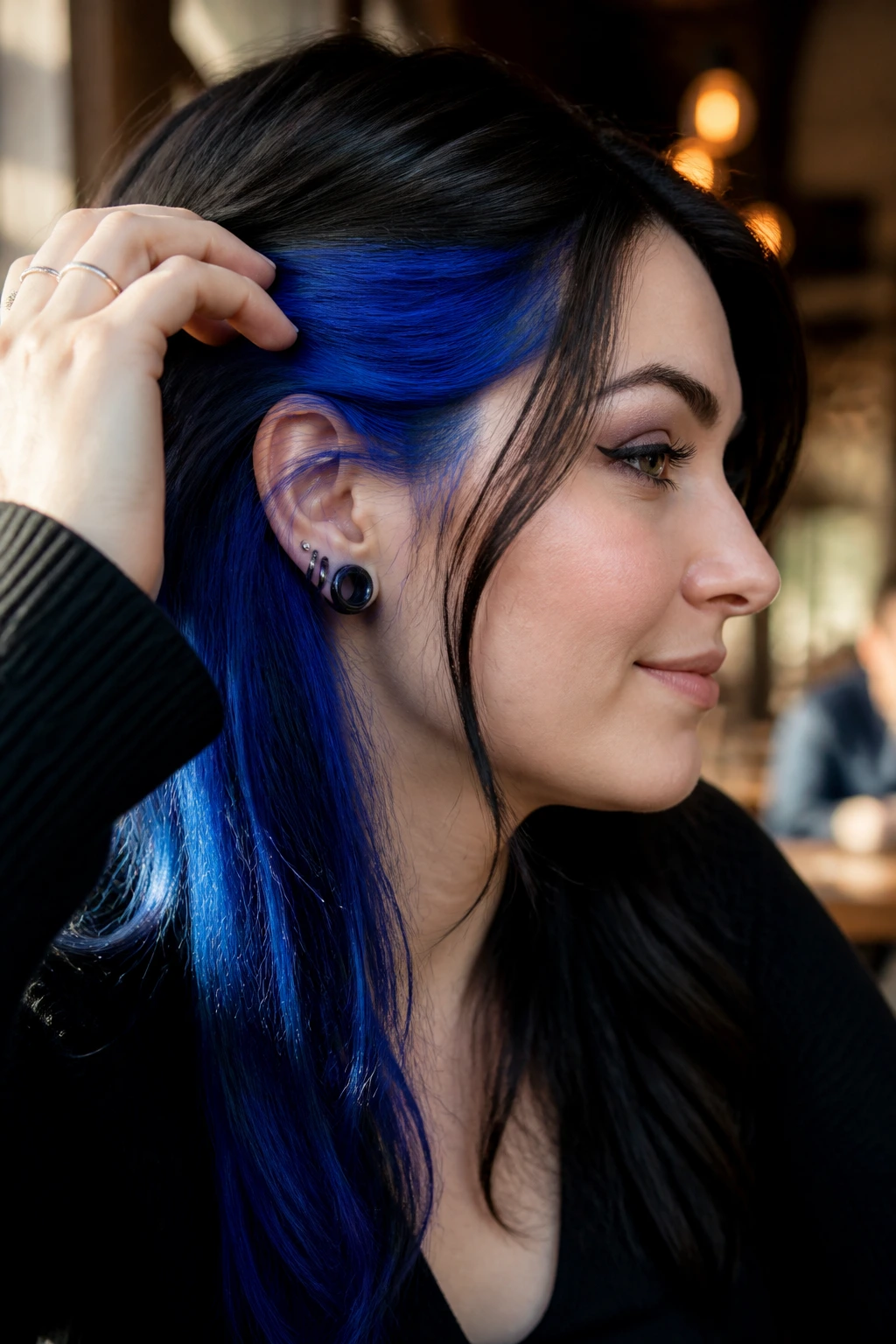 Close-up of a real person with electric blue peekaboo under jet-black hair