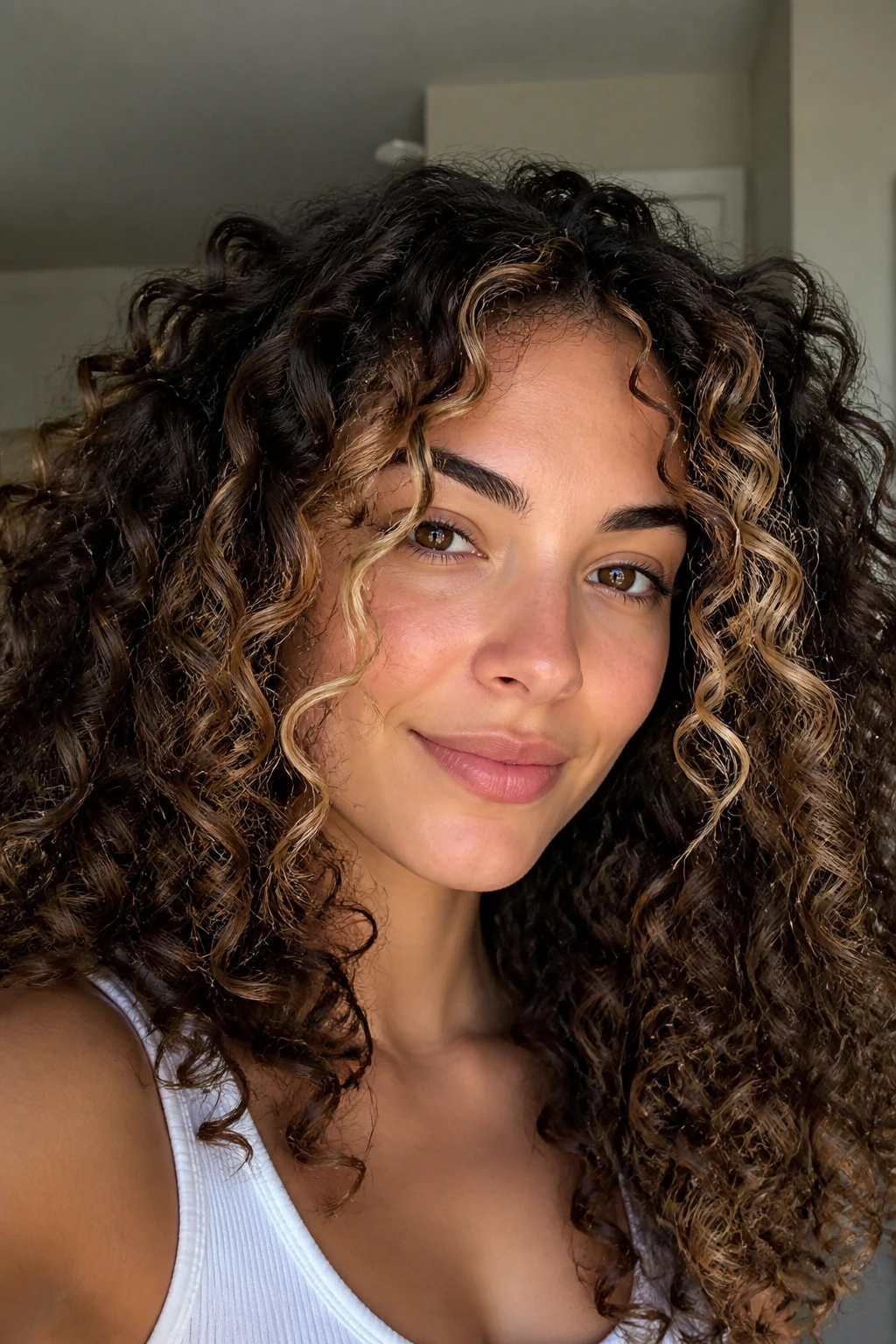 Close-up of a real woman with curly hair and face-framing highlights