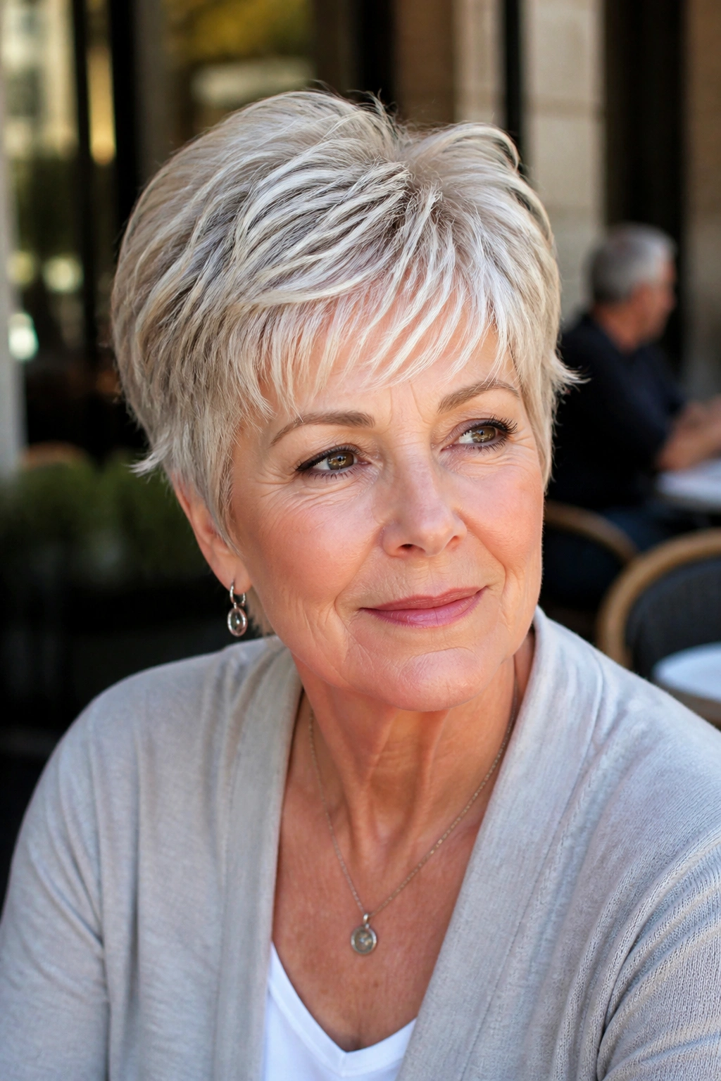 Close-up of an older woman with a feathered pixie and soft fringe in daylight.
