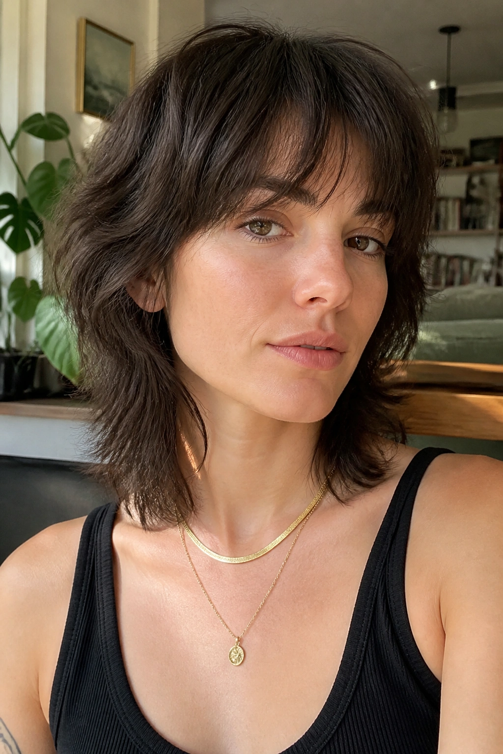 Close-up of a real woman with a grown-out wispy mullet in a cozy living room.