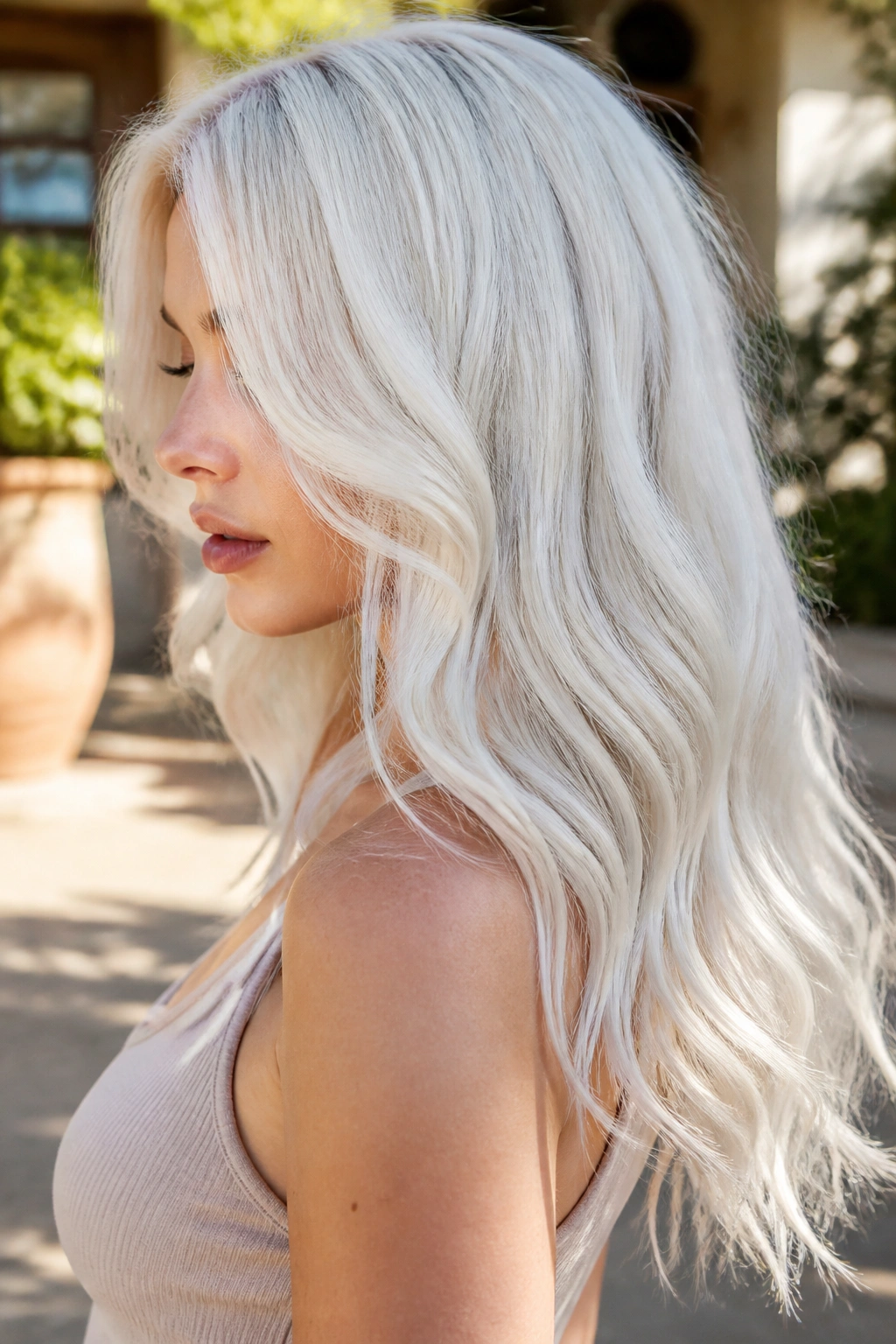 Close-up of a real woman with long icy platinum waves in sunlight
