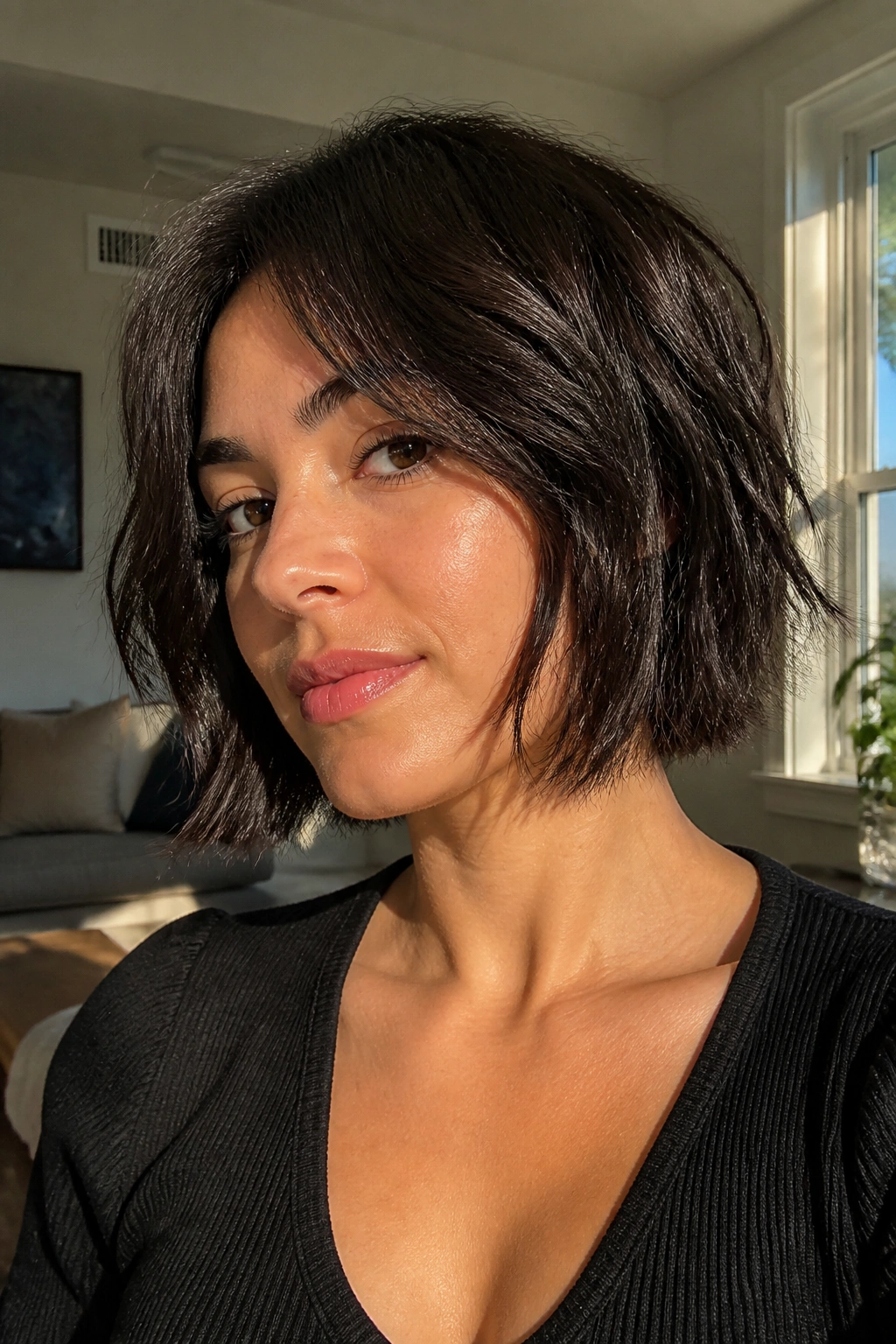 Close-up of a real woman with a jaw-grazing razor bob and choppy layers under natural window light