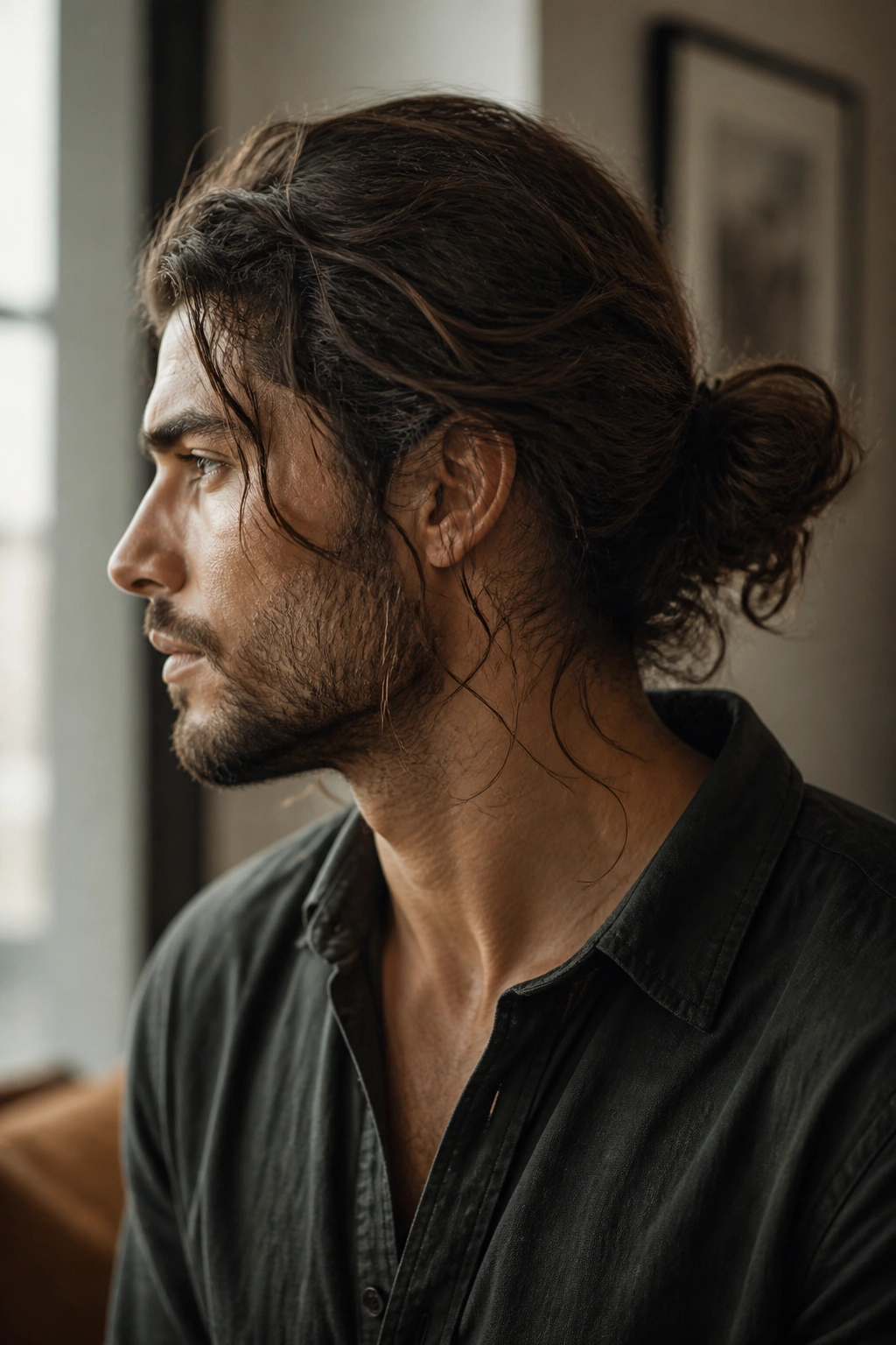 Side-profile of a man showing a loose bun with escaping strands.