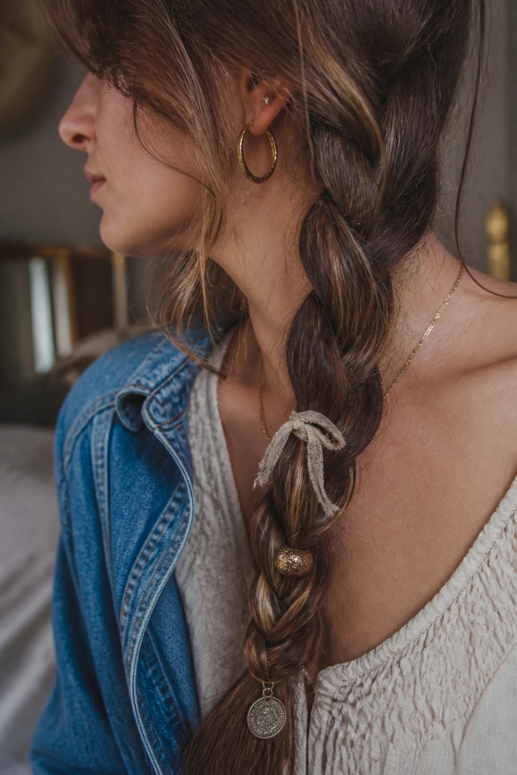 Braid adorned with mixed charm strands including ribbon bead and coin