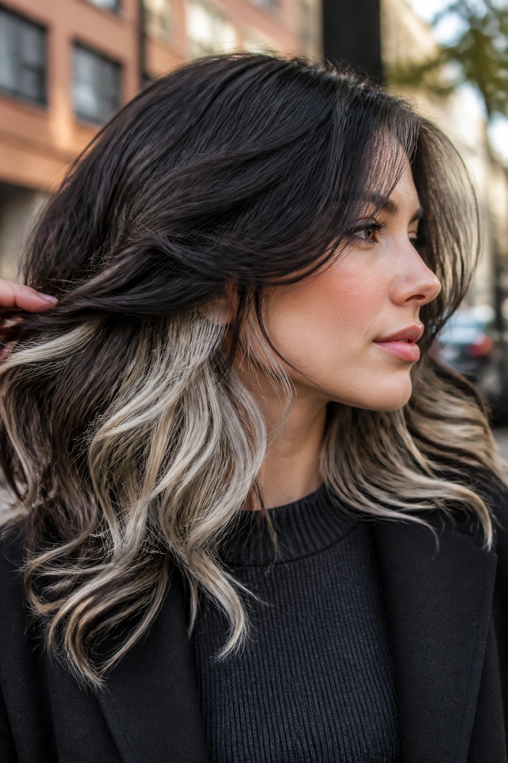 Close-up portrait of a real woman showing platinum peekaboo panels in dark hair with waves