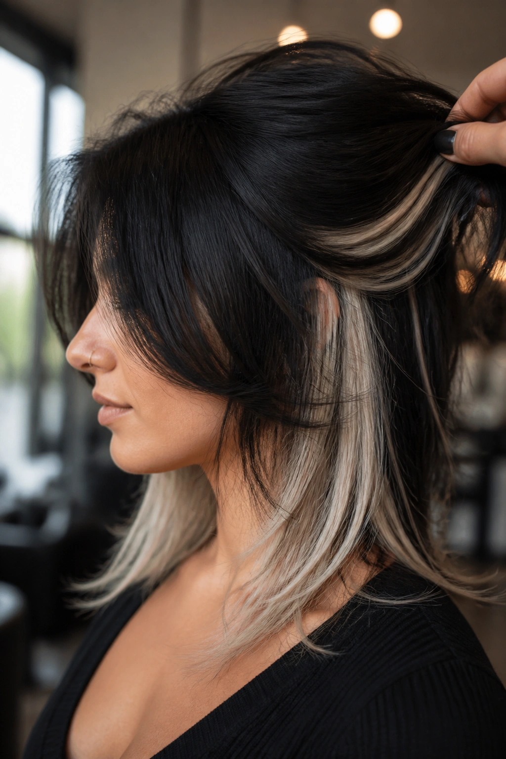 Close-up portrait of a real woman with dark layered hair and platinum peekaboo panels.