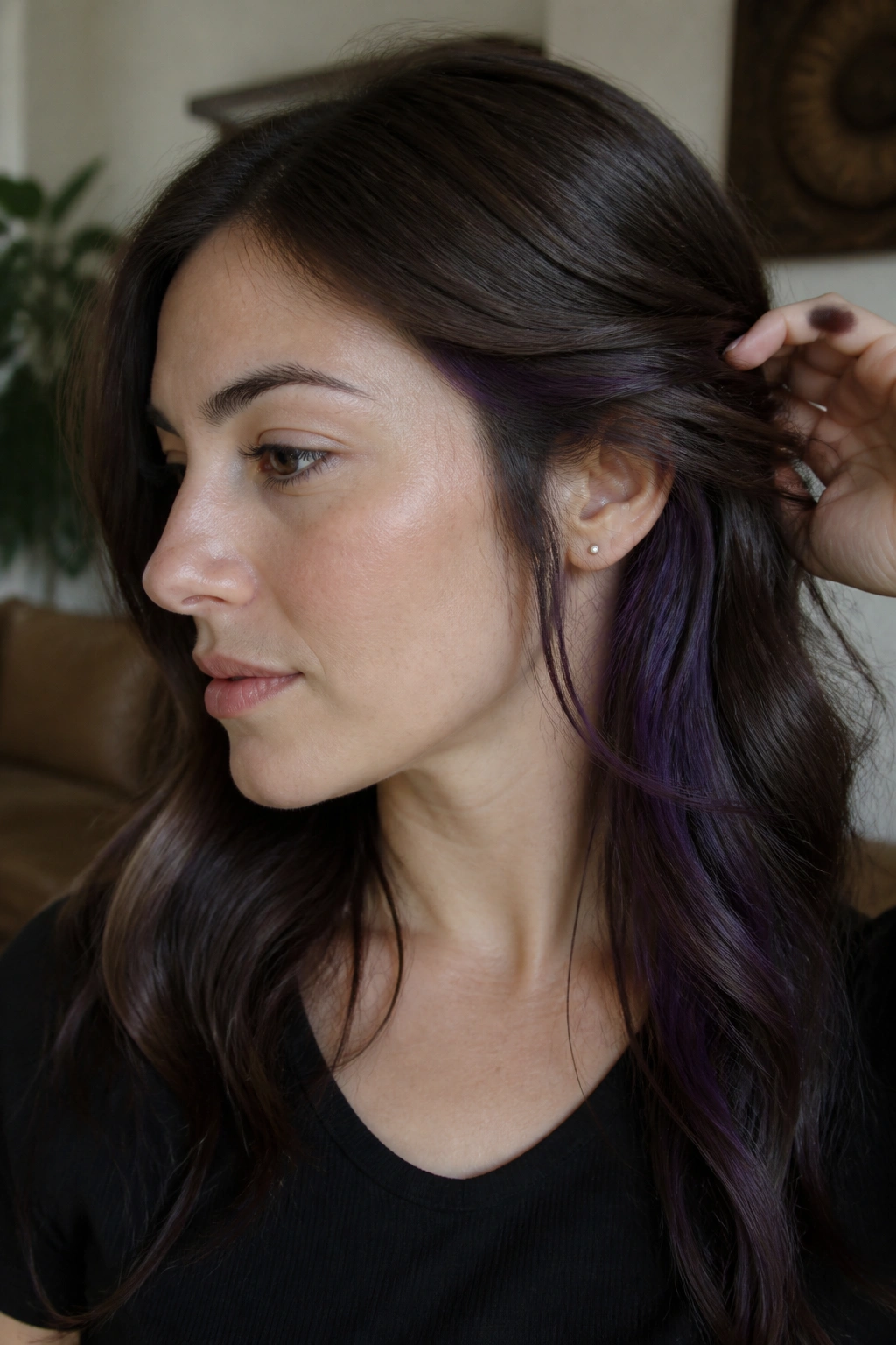 Close-up of a real woman with plum-violet hidden panels under brunette hair behind the ear.