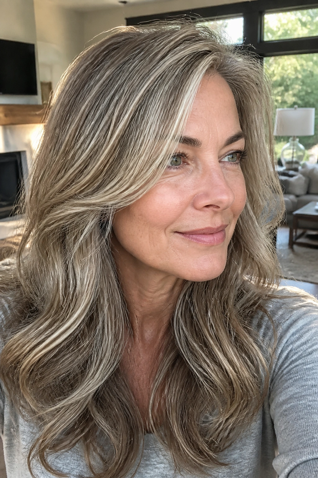 Close-up of a real woman with beige blonde reverse balayage blending grey for a lived-in look.