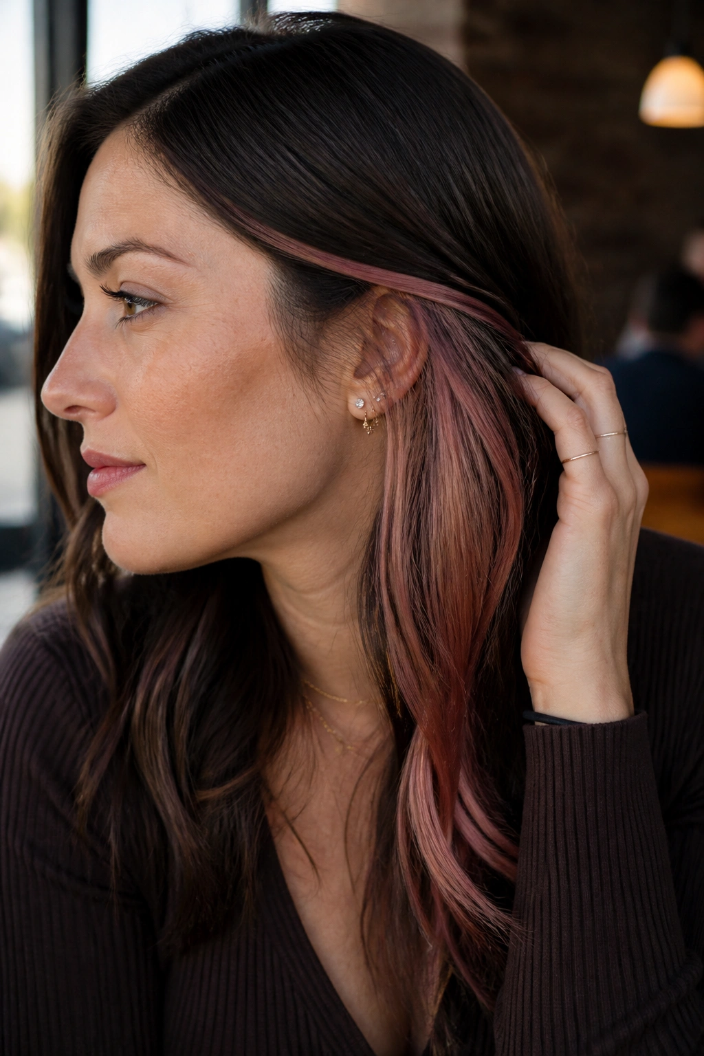 Close-up of a real person with dark brown hair showing rose gold peekaboo panels under the top layer