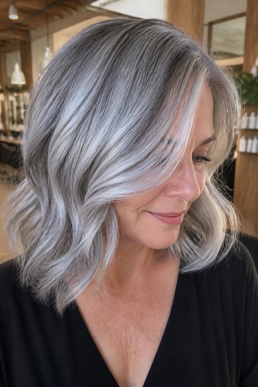 Woman with cool silver balayage blending roots to mercury tones in a salon.