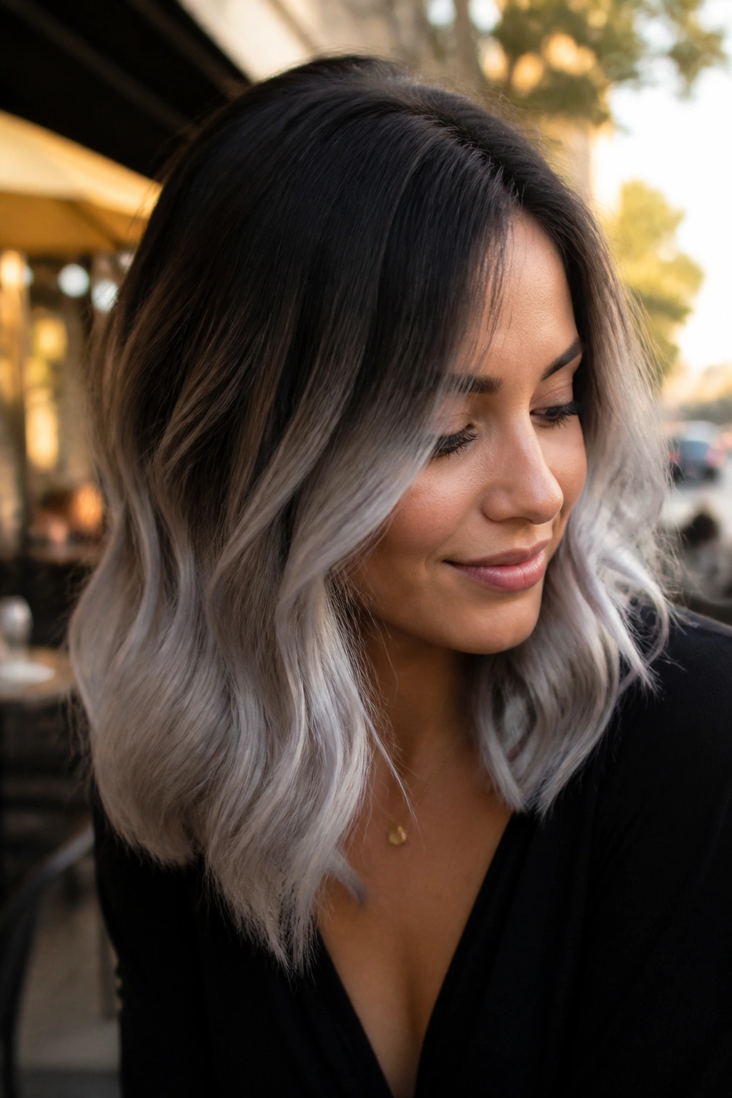 Close-up of a real woman with dark roots fading to silver ombre on shoulder-length hair.