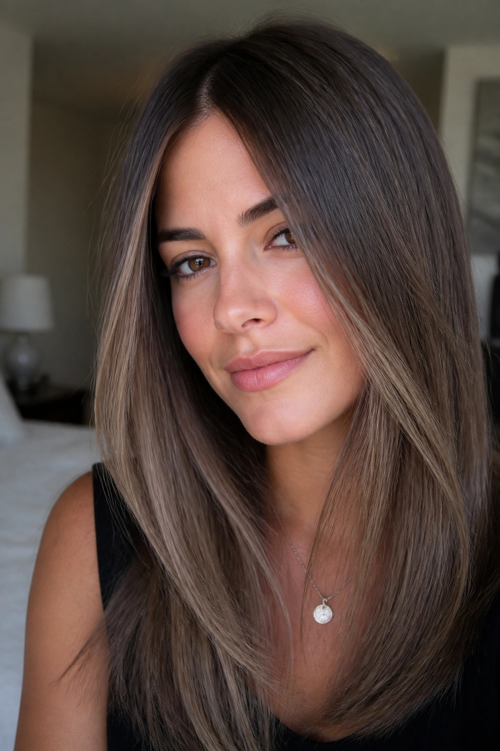 Close-up of a brunette with smoky beige balayage in natural window light