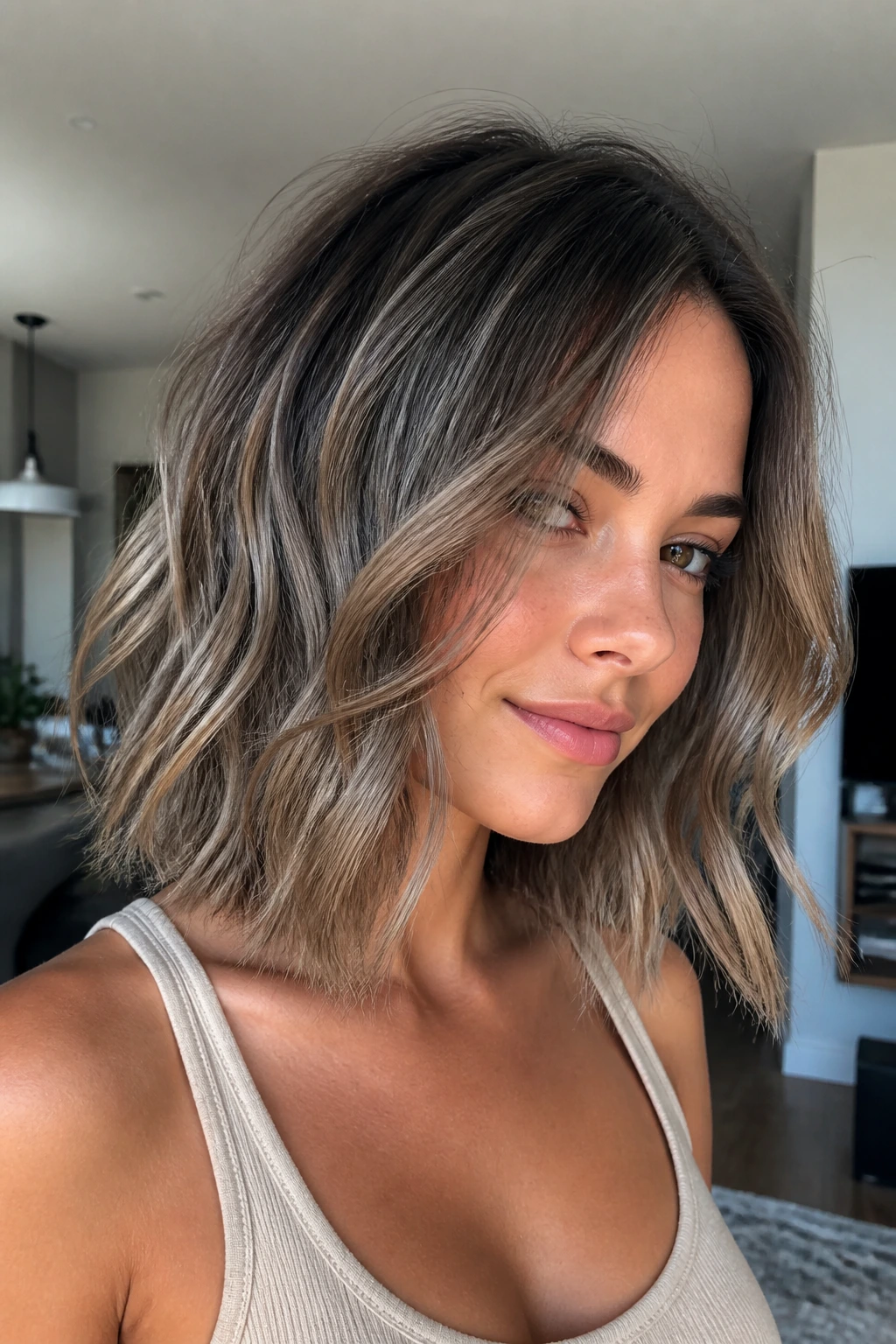 Portrait of a woman with smoky bronde balayage on a tousled lob.