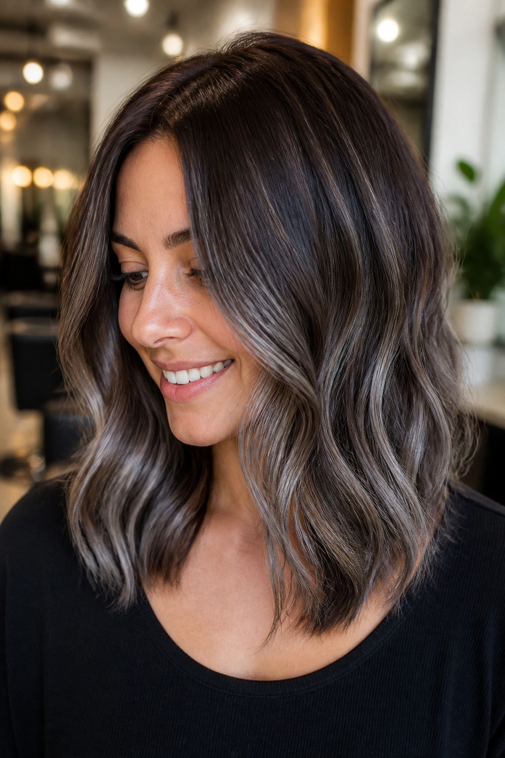 Portrait of a real person with smoky silver balayage through mid-lengths in soft waves.