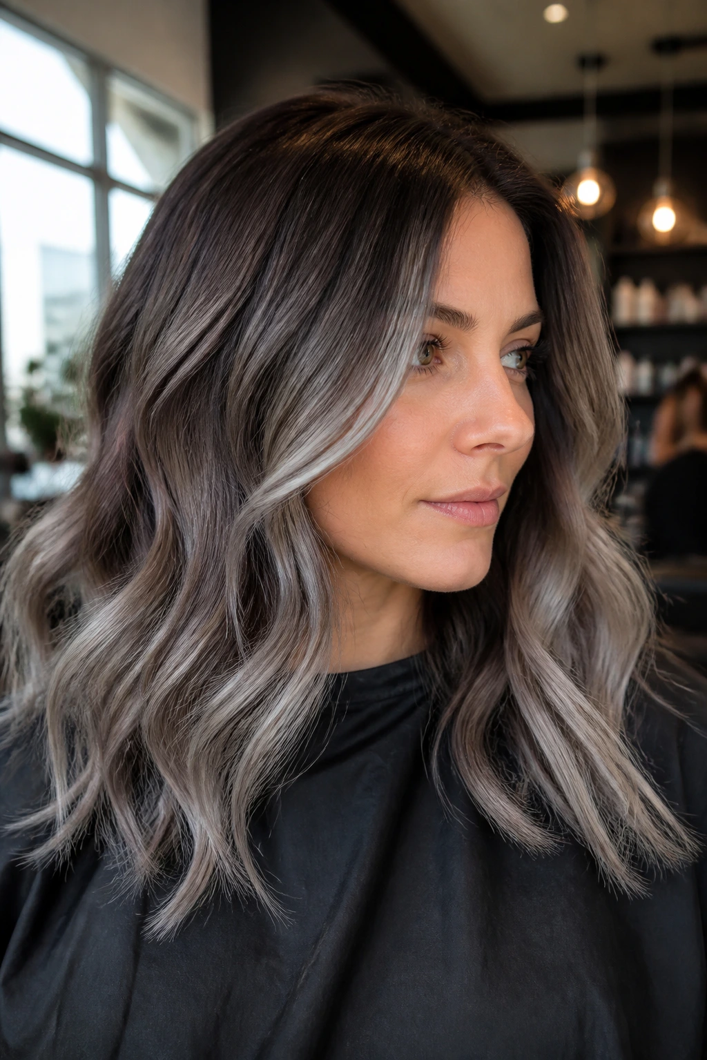 Close-up of a real woman with smoky silver balayage on dark brown hair