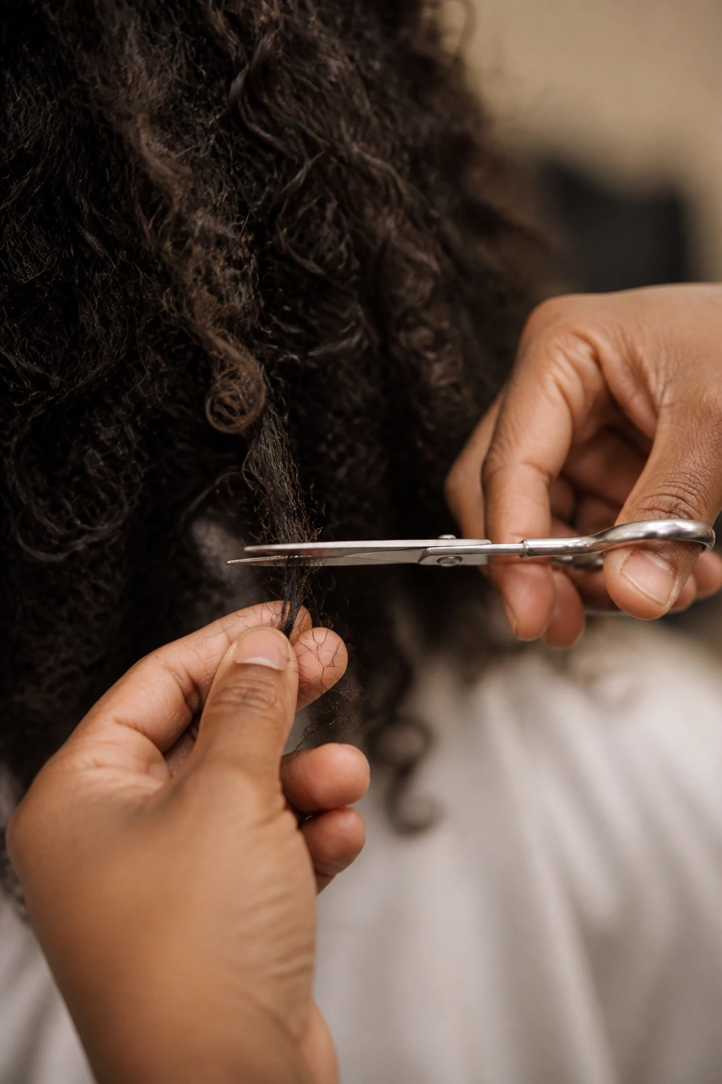 Close-up of hair being trimmed to remove split ends in warm light