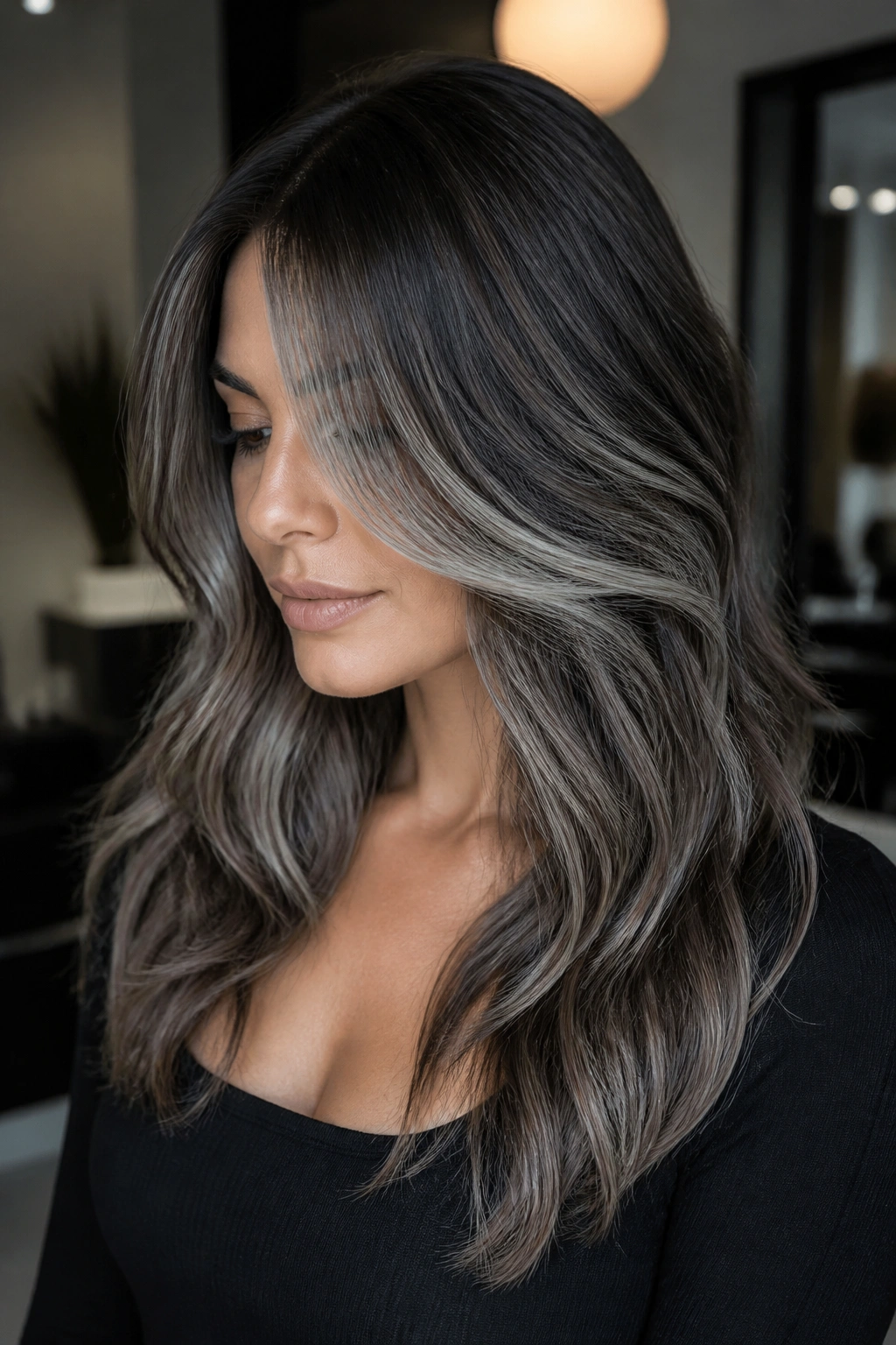 Close-up of a real woman with steel silver balayage on layered brown hair highlighting layers