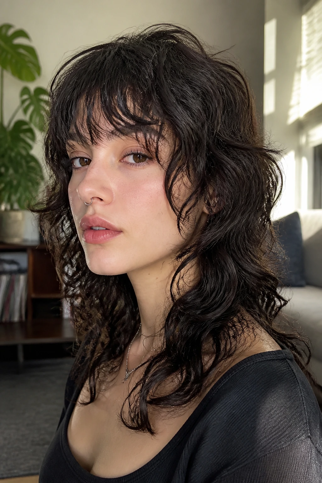 Close-up portrait of a real person with subtle emo wolf cut for loose curls in a sunlit living room.