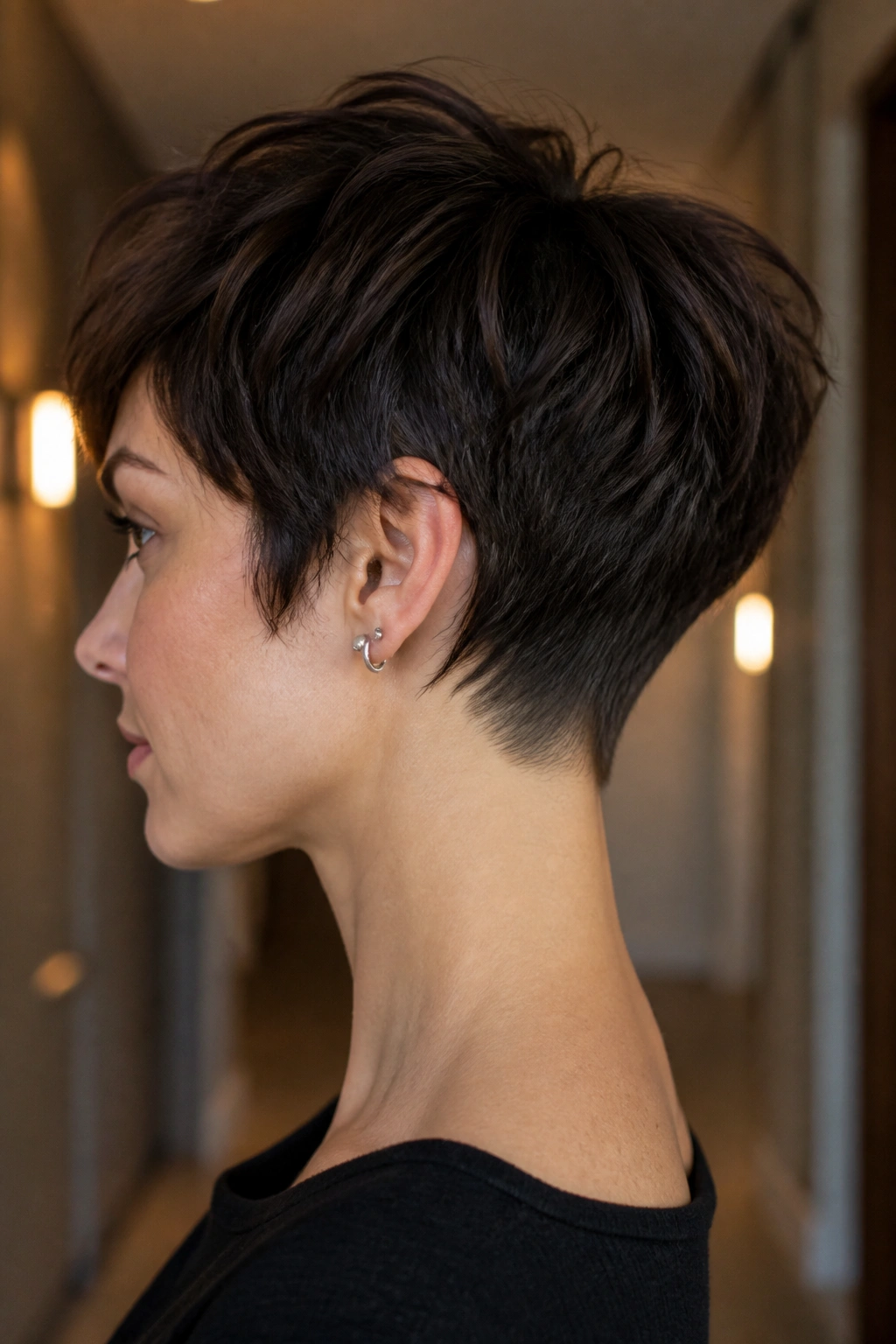 Side-profile of a real person with tapered nape wolf pixie and clean neckline.