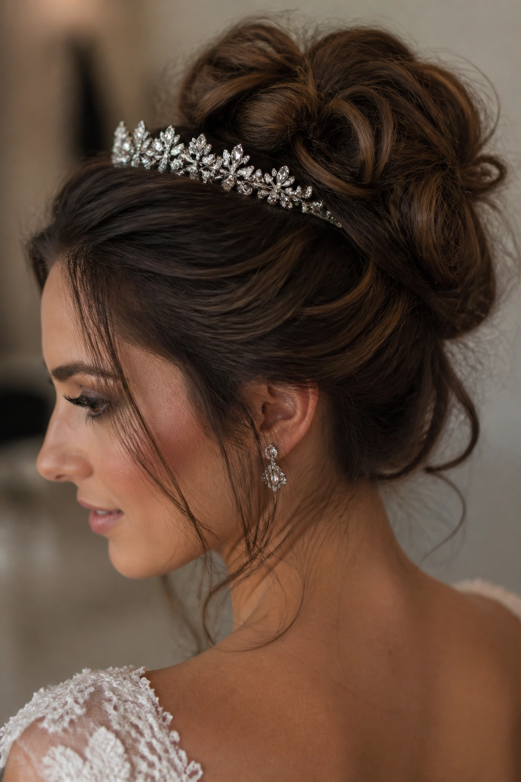 Close-up of a bride's textured messy bun with a sparkle tiara in a softly lit dressing room