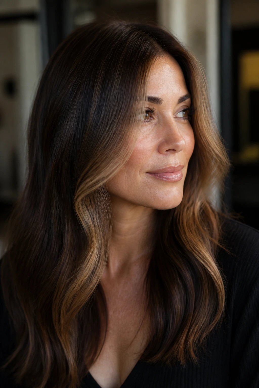 Close-up of a real woman with toffee money piece highlighting around the face on a brunette base.