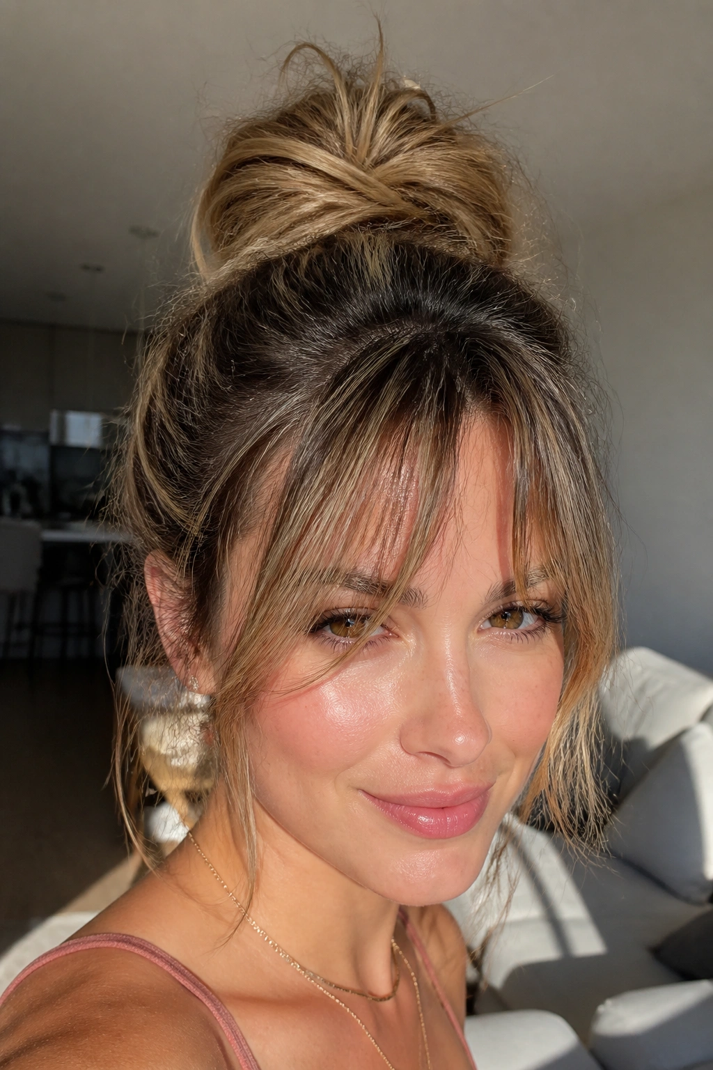Close-up of a real person with a high textured top knot and piecey fringe in a sunlit room