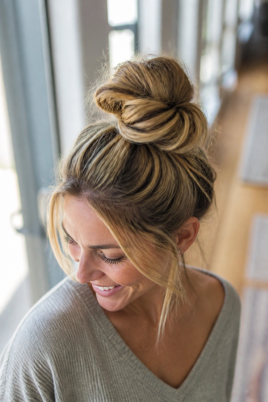 Real woman with a messy top knot and loose strands around the face.