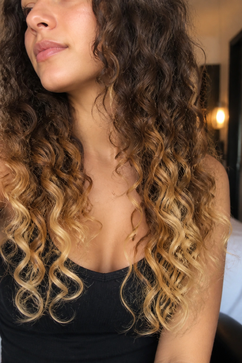 Close-up of real woman with vanilla cream ends on long curly hair.
